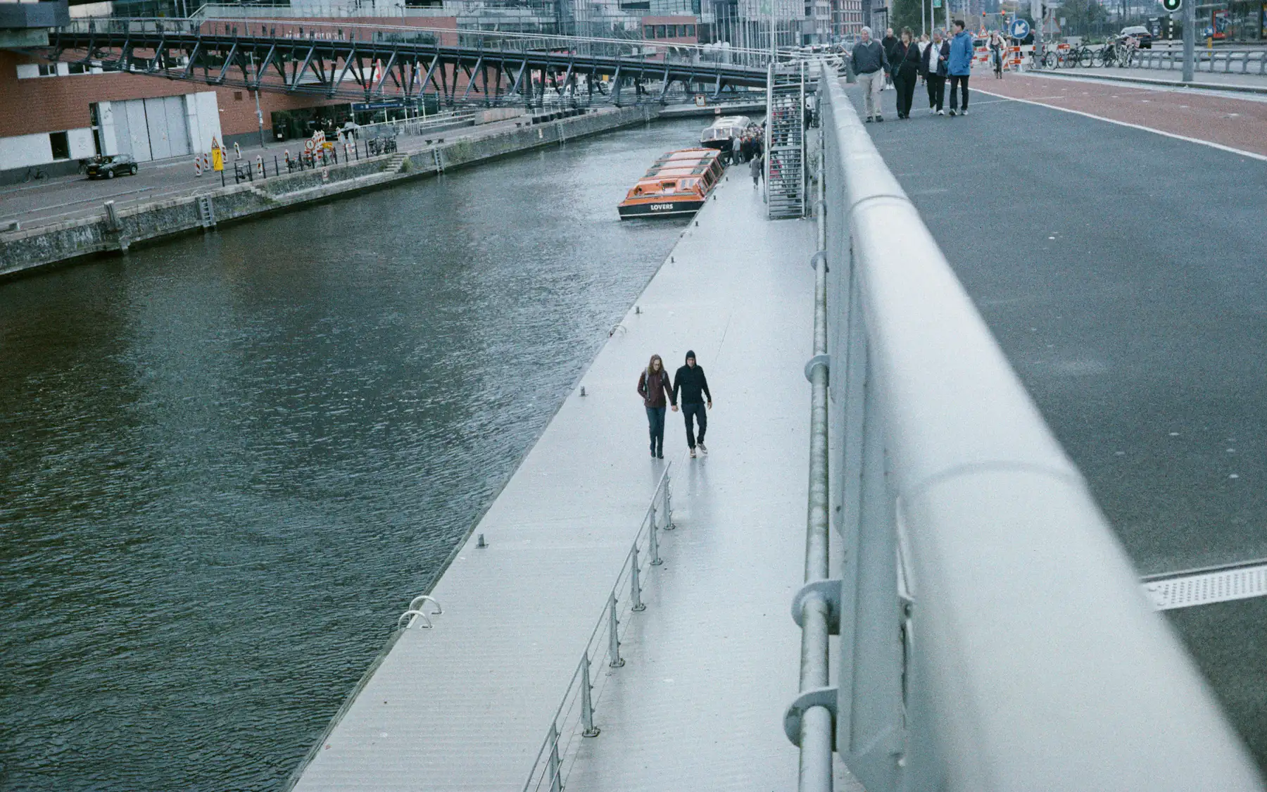 A couple walking hand in hand along an Amsterdam canal walkway