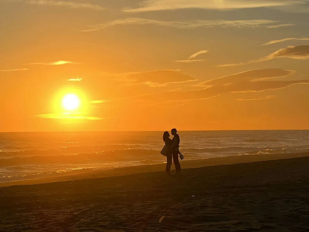 A couple standing together on a Barcelona beach at sunset