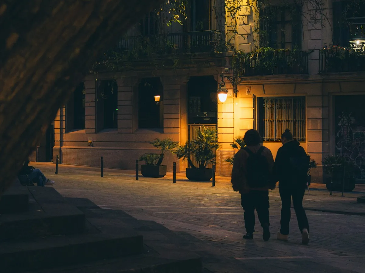 Two people walking down a quiet Barcelona street at night