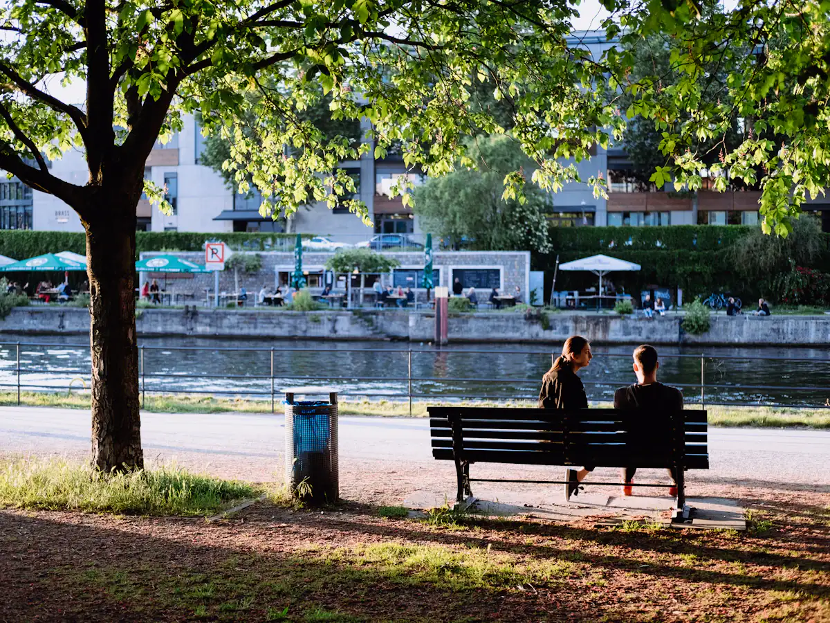 Two people sitting on a bench beside the river Spree in Berlin