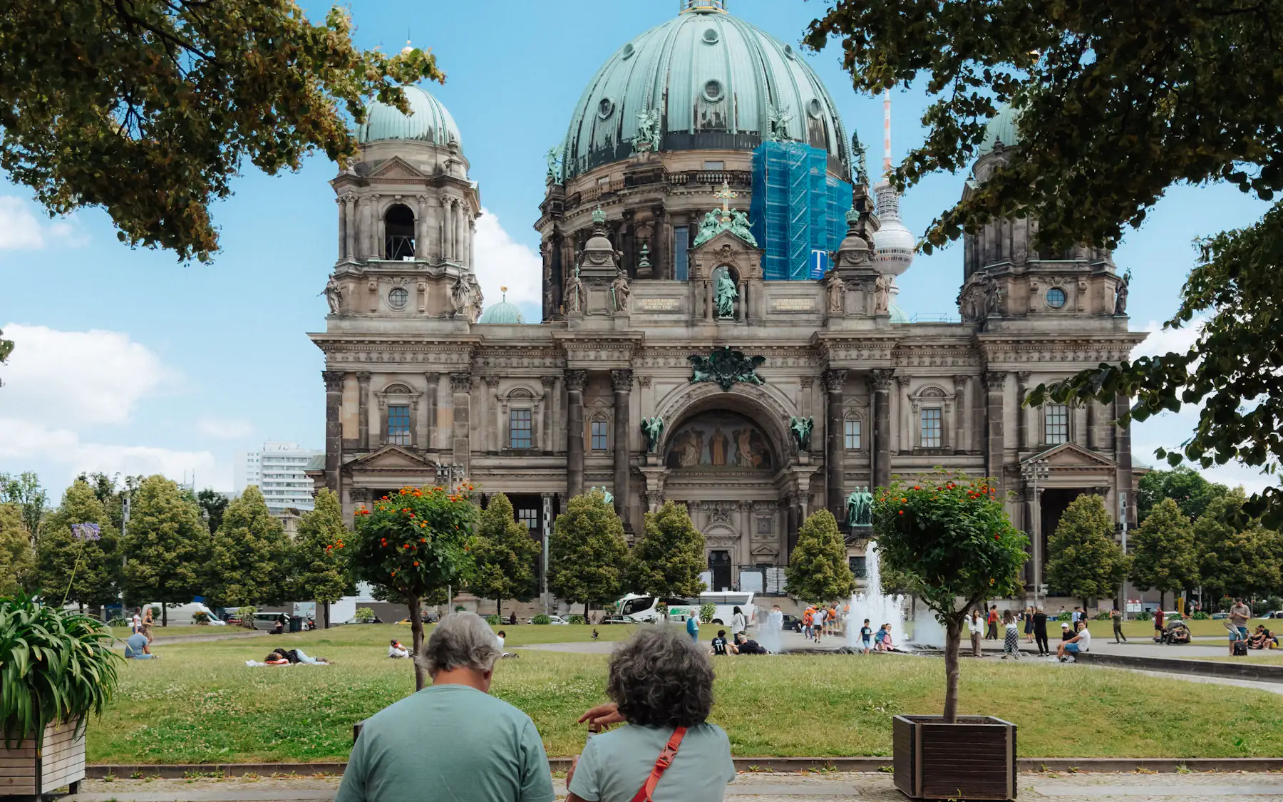 A couple sitting on a bench in front of Berlin Cathedral, photographed from behind