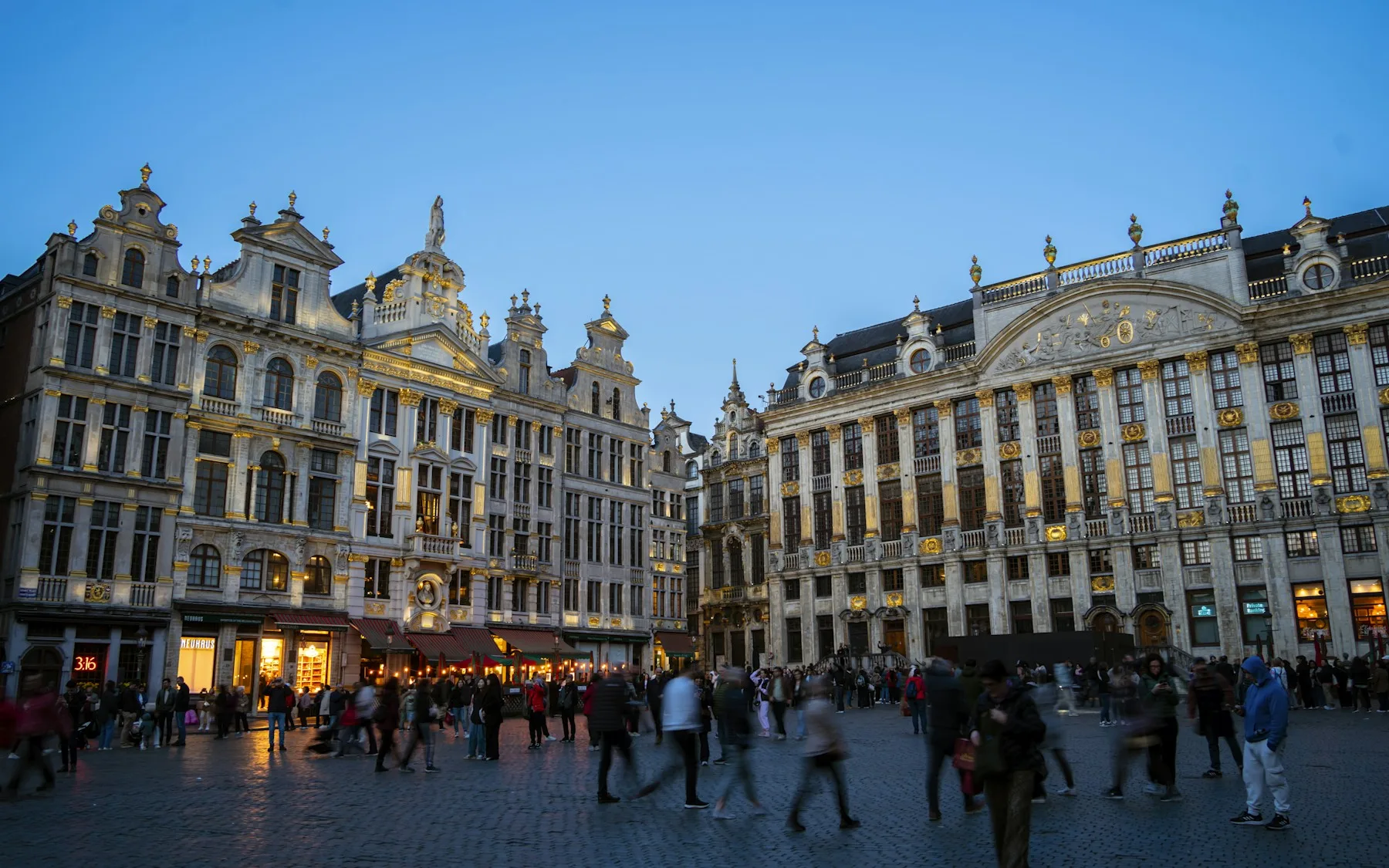 People walking across the Grand-Place in Brussels at dusk