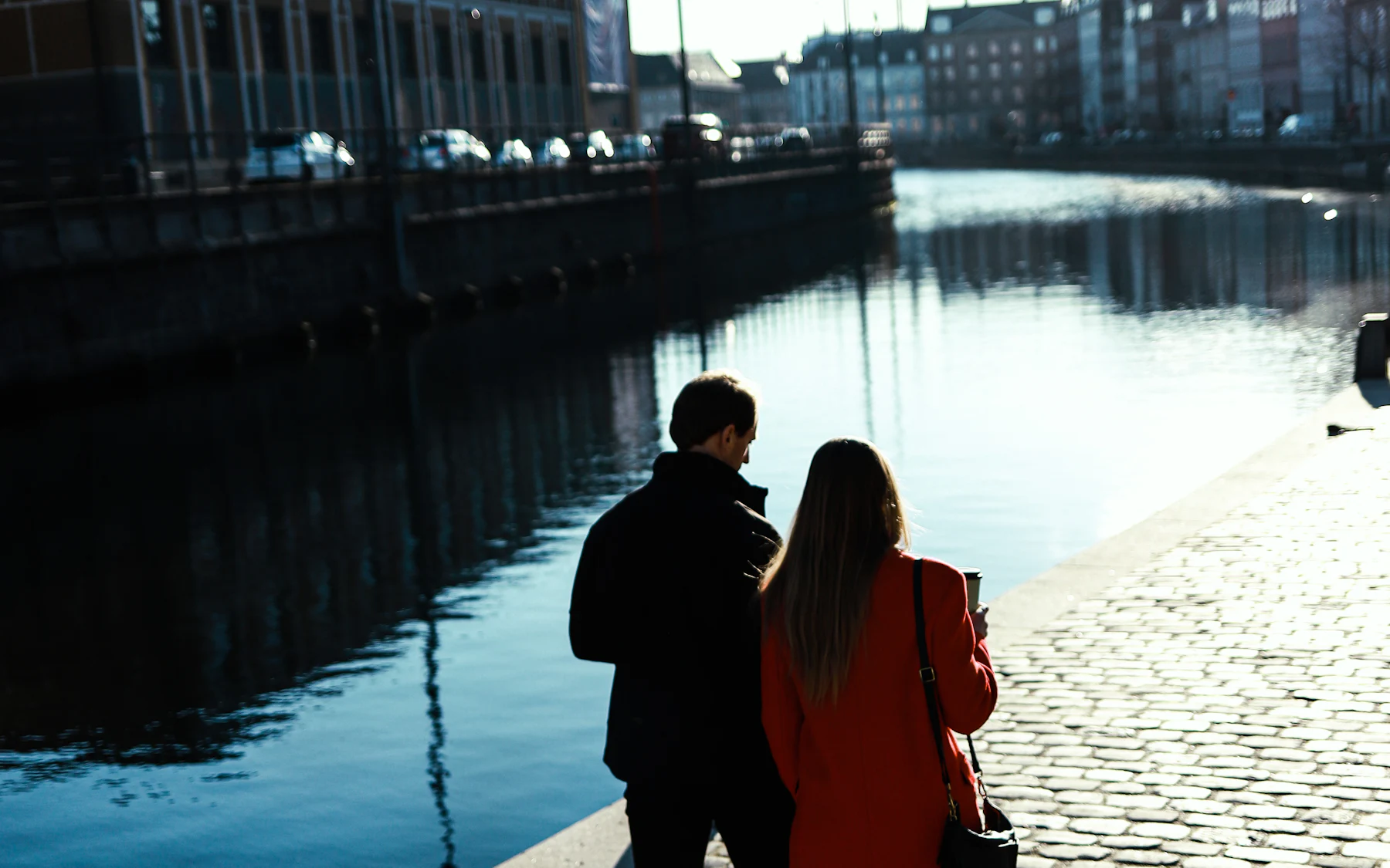 A couple standing on a cobbled Copenhagen quay beside the water