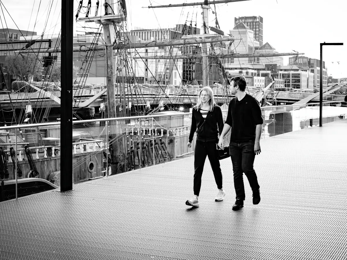 A couple walking hand in hand beside a tall ship on the Dublin docks