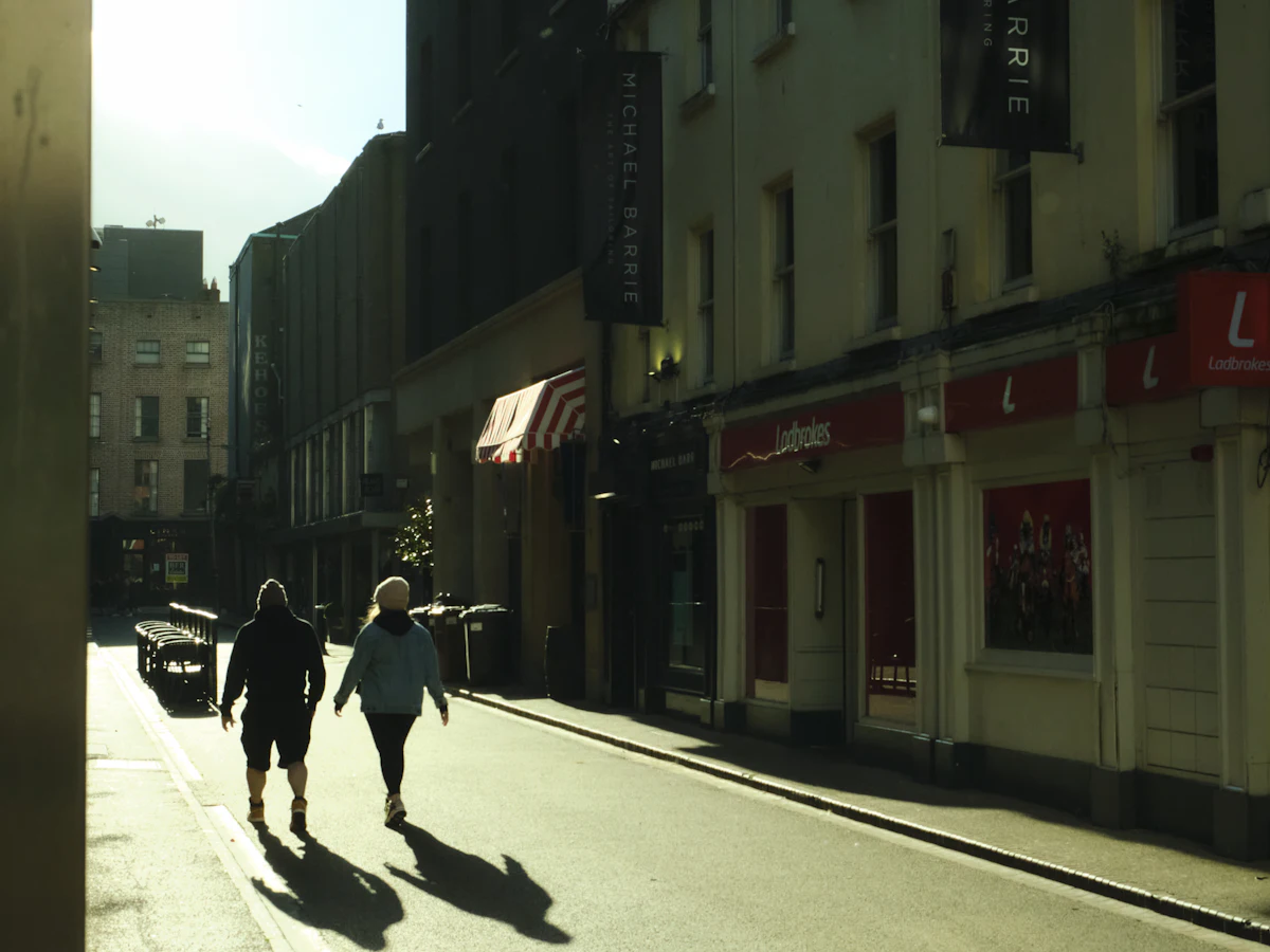Two people walking down a sunlit Dublin street
