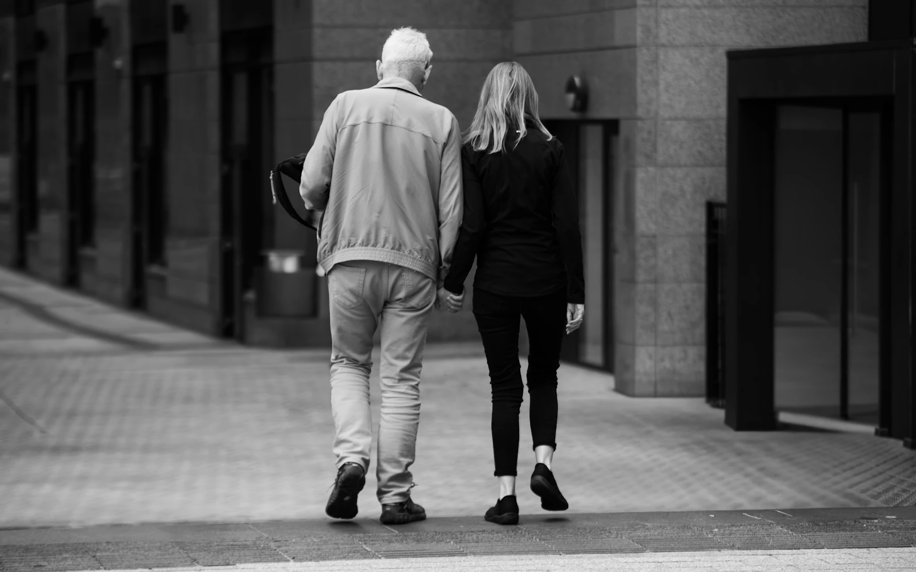 Two people walking hand in hand down a Dublin street, photographed from behind