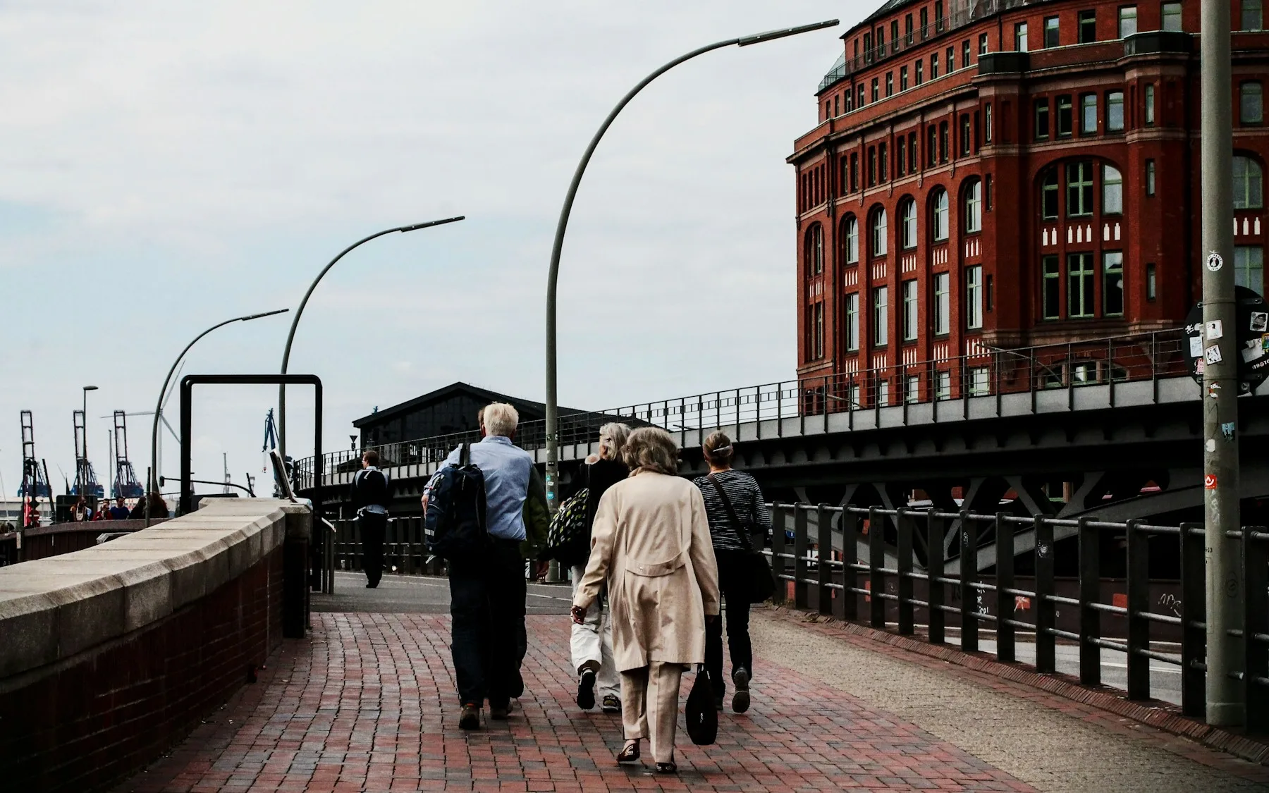 A couple walking along a cobbled path beside the Speicherstadt warehouses in Hamburg
