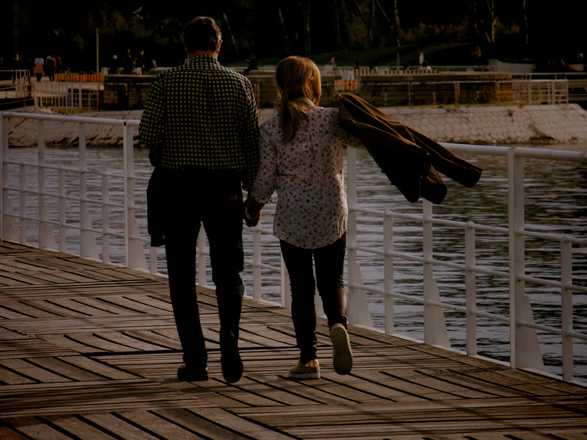 A man and a woman walking along a wooden dock by the river in Lisbon