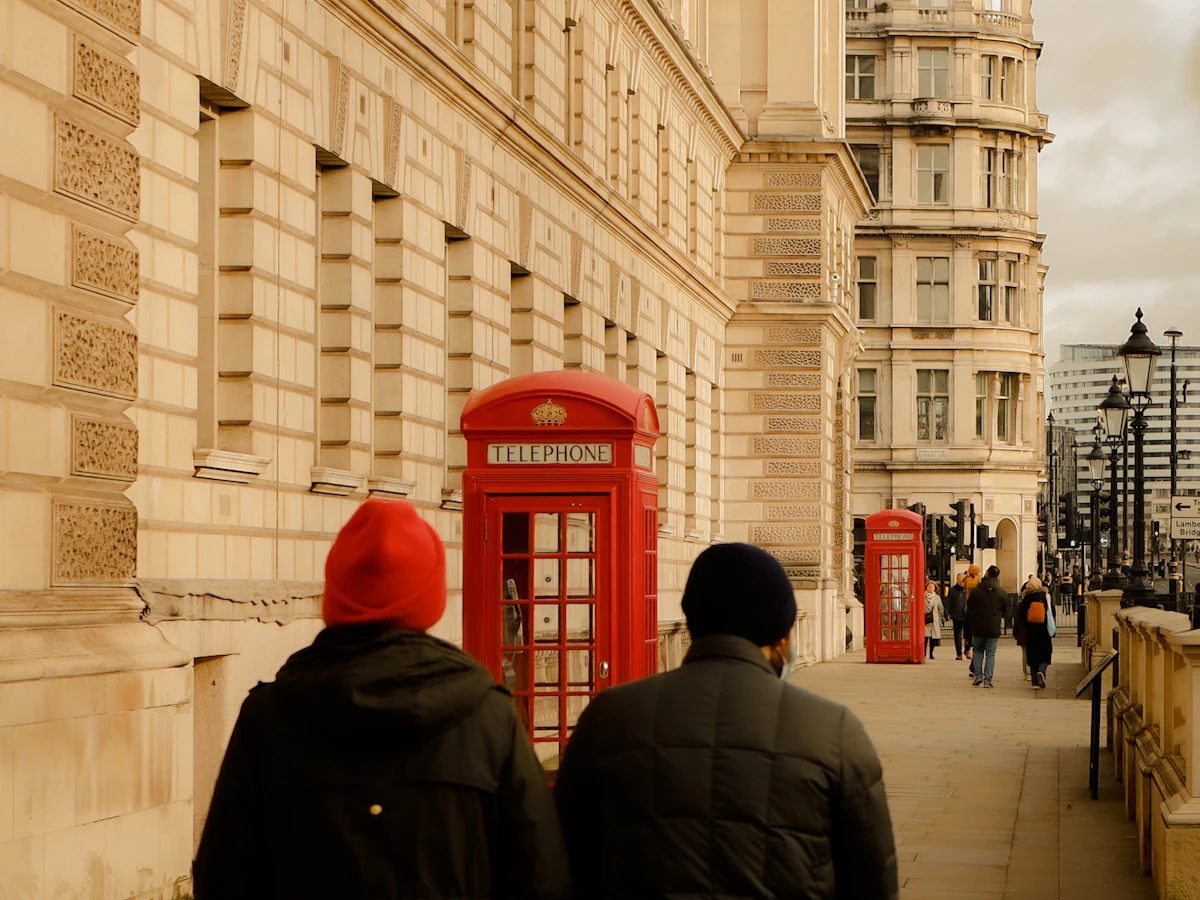 Two people walking down a London street past a red telephone box