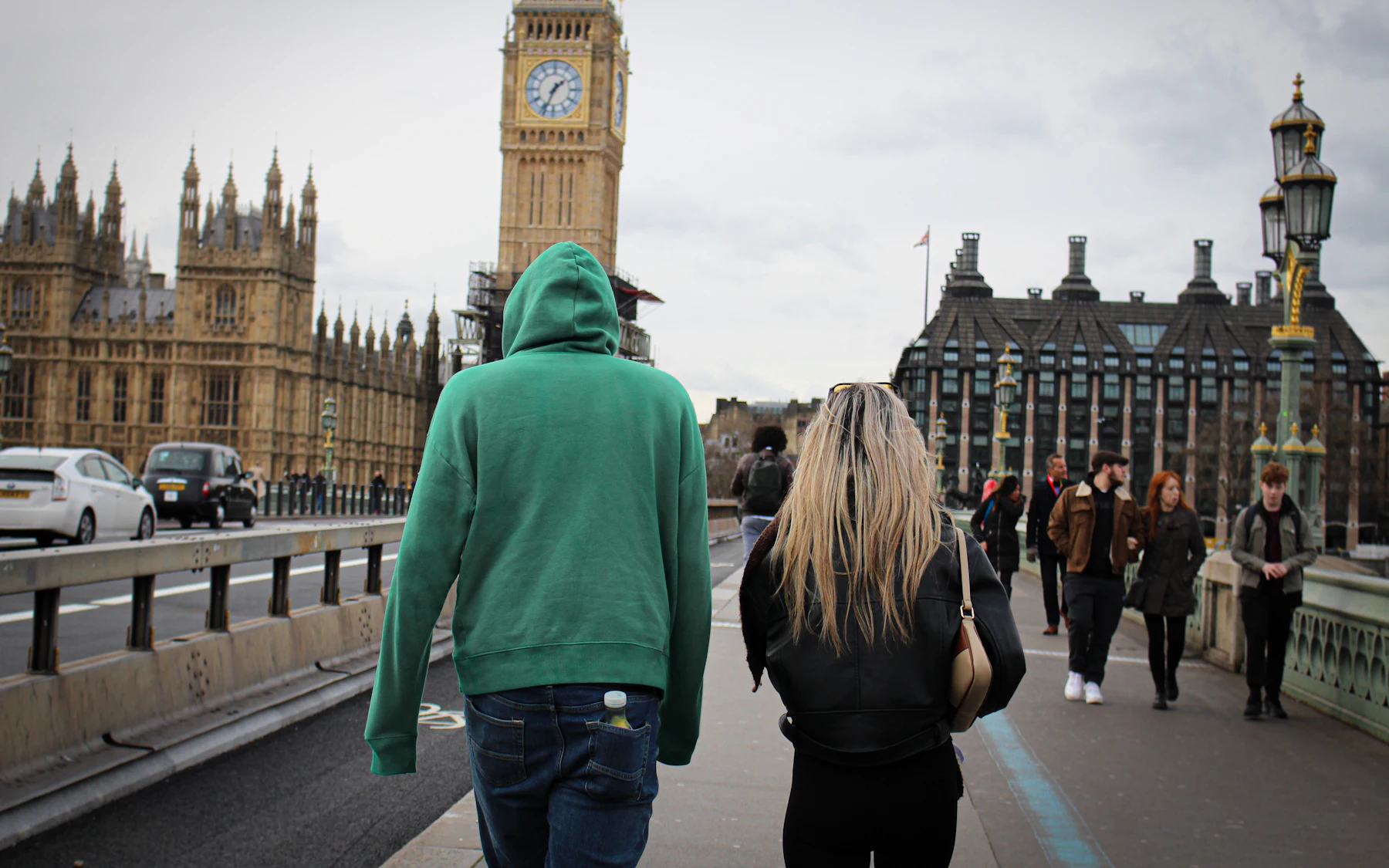 A couple walking across Westminster Bridge towards Big Ben, photographed from behind