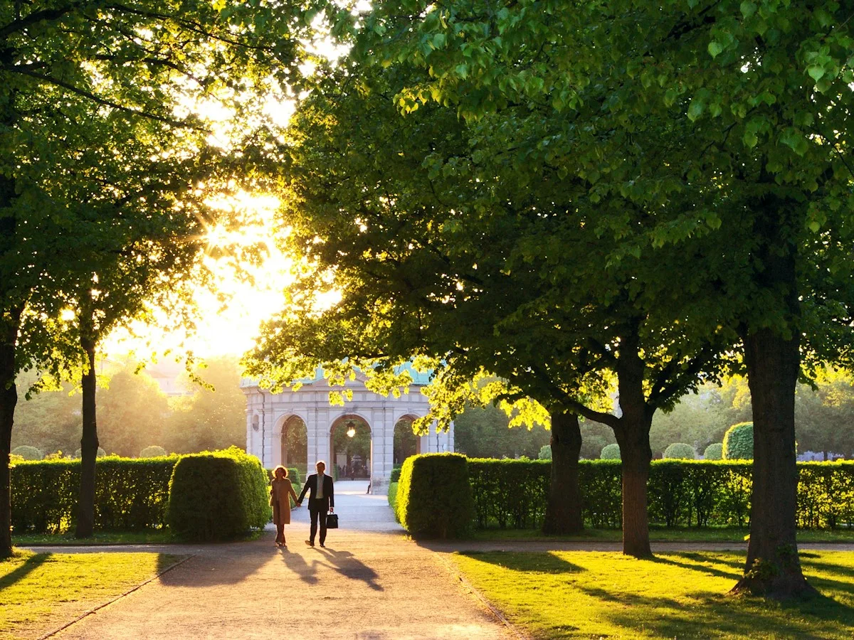 Two people walking through a Munich park at golden hour
