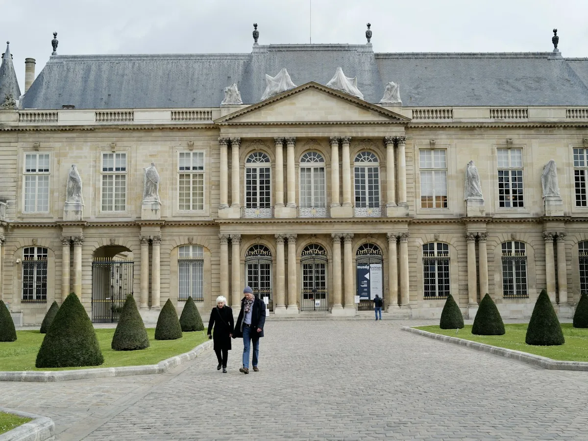 Two people walking towards a grand historic building in Paris