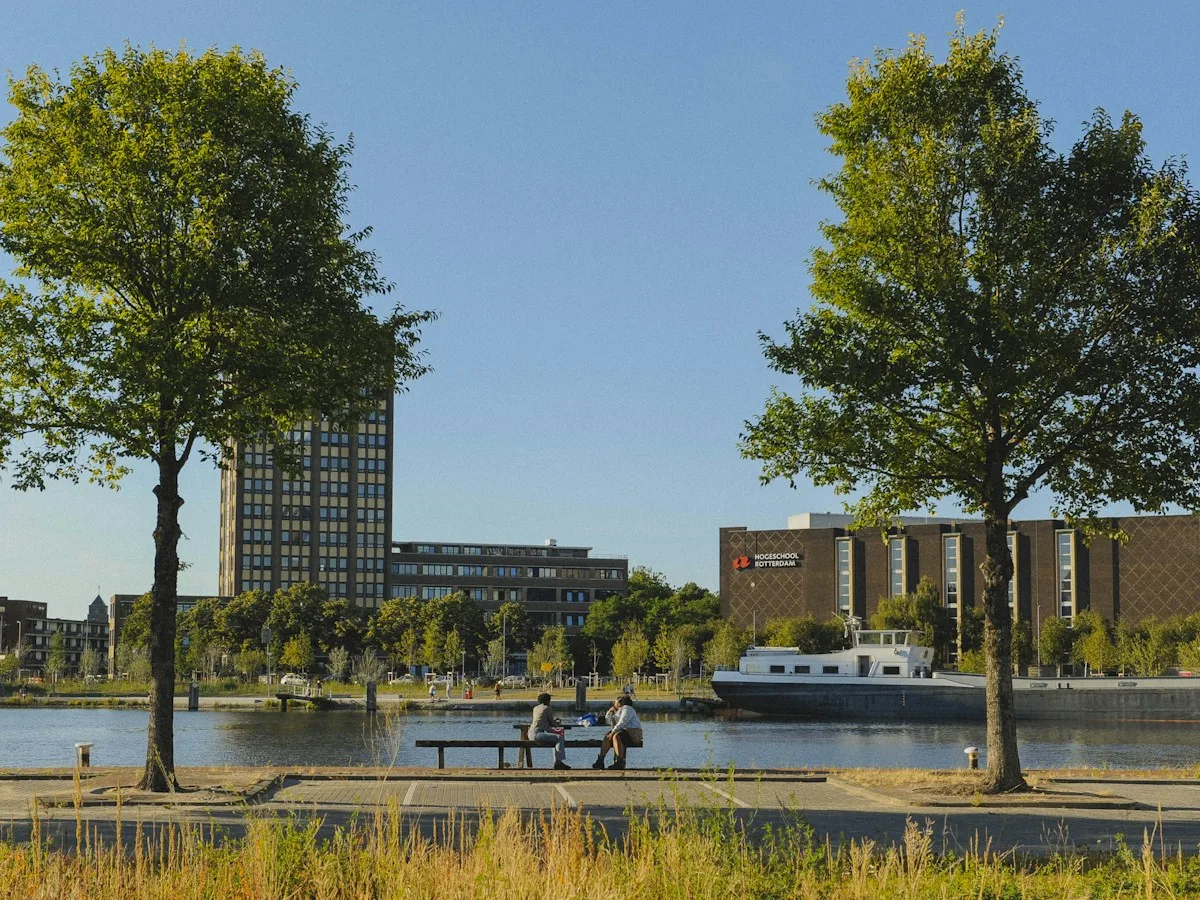 Two people sitting on a bench by the river in Rotterdam