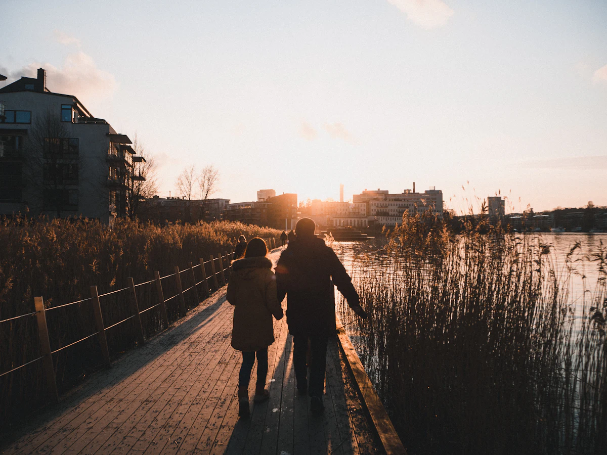 Two people walking along a Stockholm waterfront at sunset