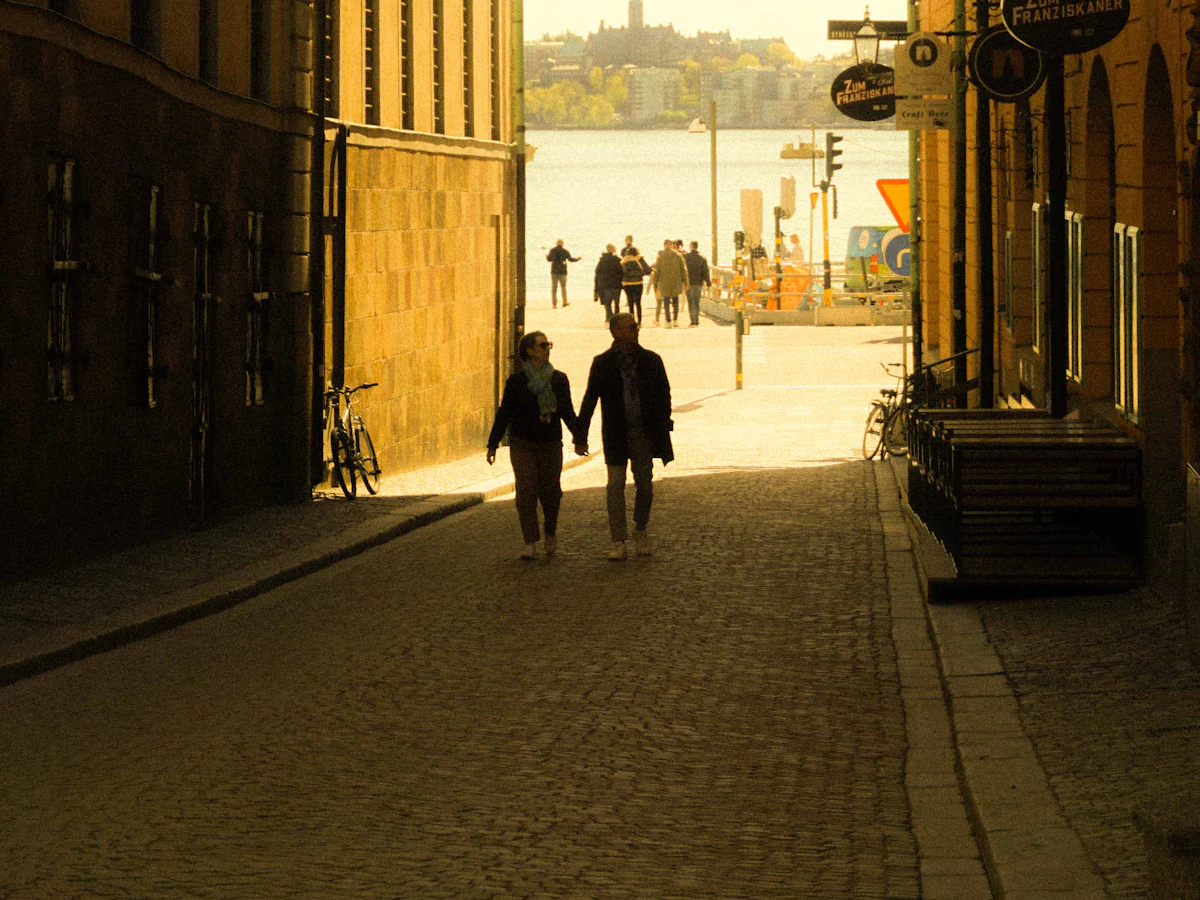 Two people walking down a narrow Stockholm alley towards the water
