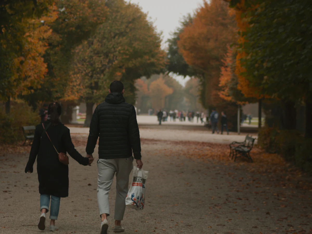 A man and a woman walking through a Vienna park in autumn