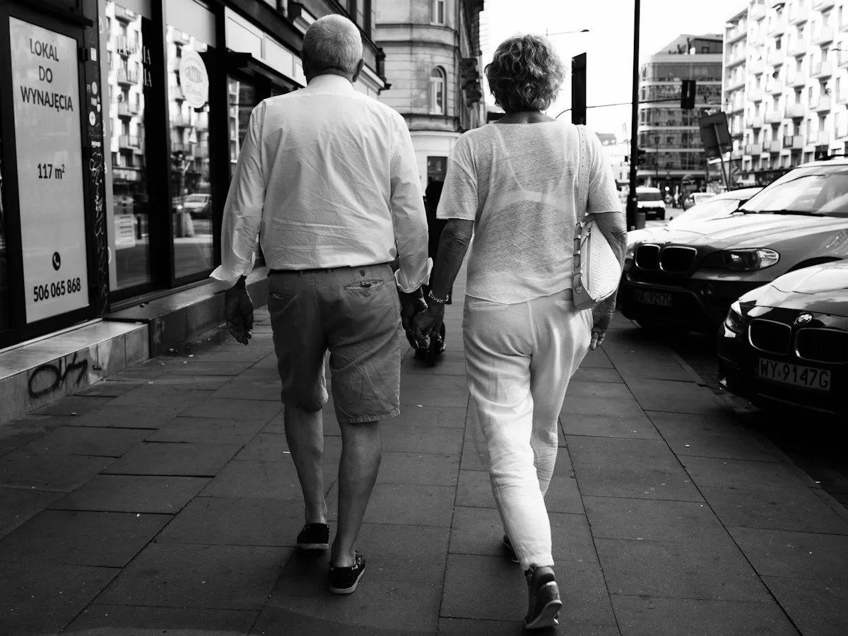 A man and a woman walking down a Warsaw pavement, in black and white